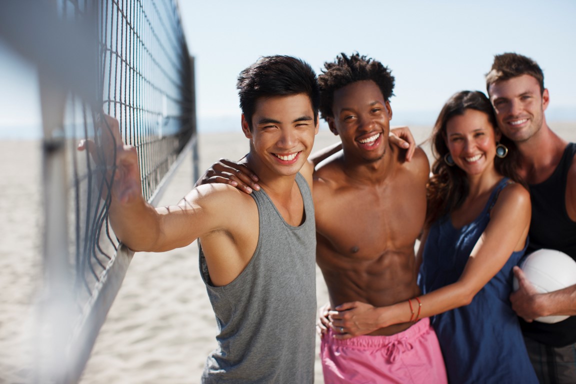 Friends smiling on beach volleyball court
